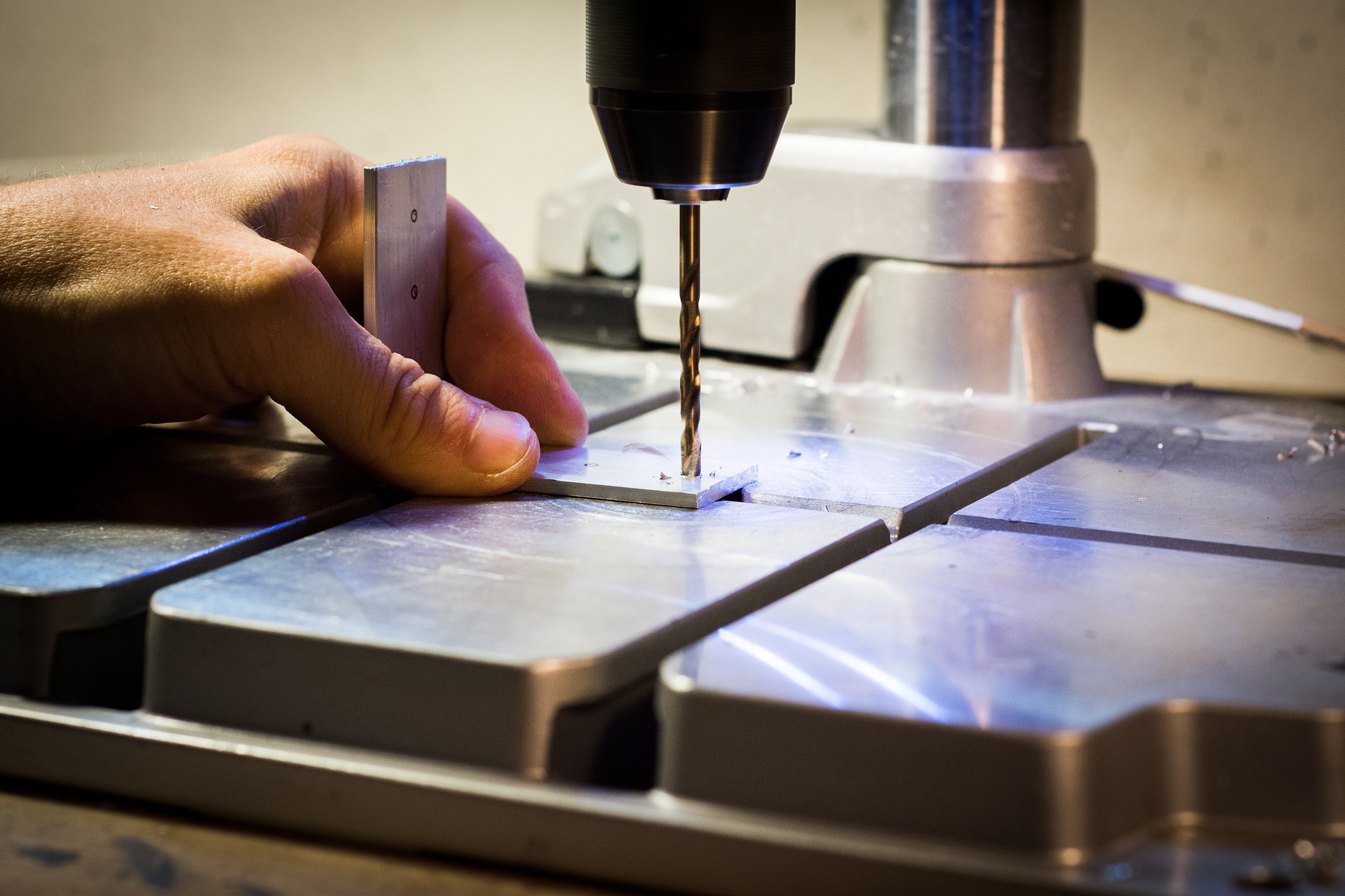 Profissional perfurando uma peça de alumínio durante o processo de fabricação
