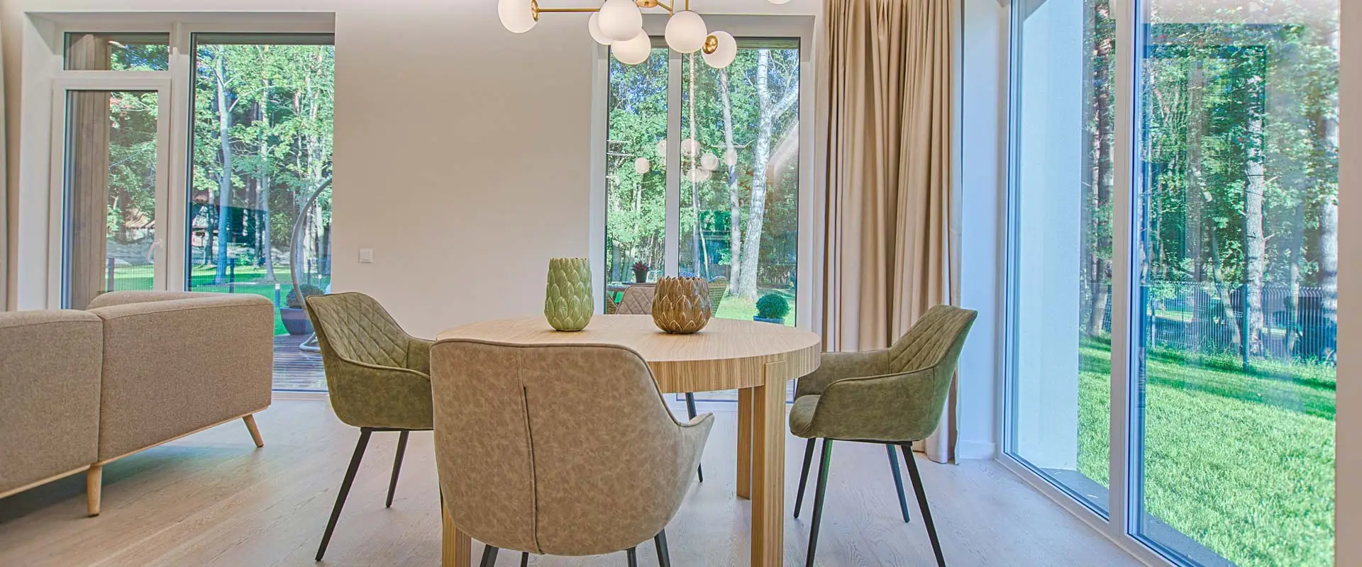 Sala de estar com grandes janelas de alumínio e vidro com vista para o verde